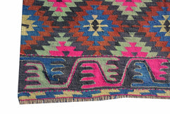 A vintage handmade Turkish kilim rug featuring a geometric pattern in vibrant neon colors.