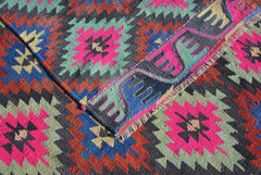A vintage Turkish kilim rug featuring a geometric pattern in vibrant neon and earthy tones.