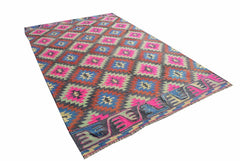 A rectangular vintage Turkish kilim rug featuring a geometric pattern in neon pink, blue, and grey.