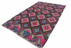 A rectangular vintage Turkish kilim rug featuring a geometric diamond pattern in neon and dark tones.