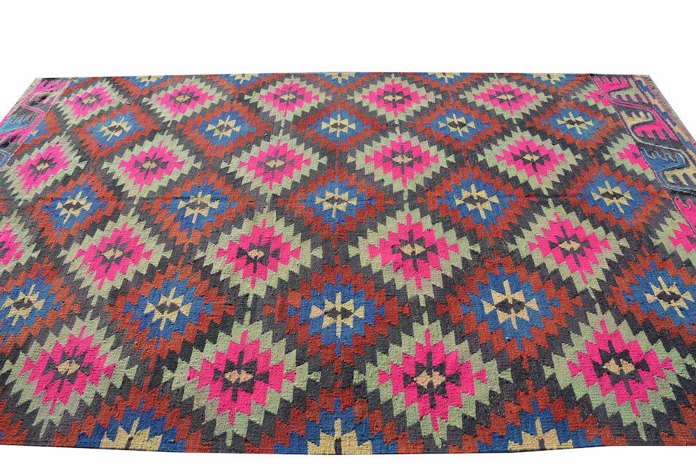 A vintage handmade Turkish kilim rug featuring a geometric diamond pattern in neon and earth tones.