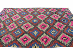 A vintage handmade Turkish kilim rug featuring a geometric diamond pattern in neon and earth tones.