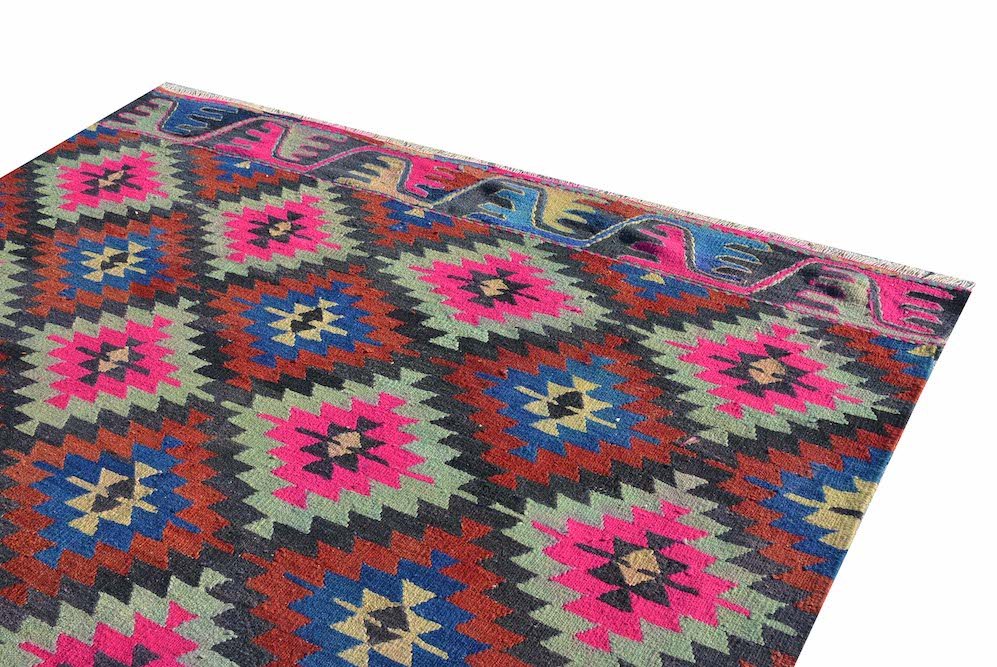 A vintage Turkish kilim rug featuring a geometric diamond pattern in vibrant neon and earthy tones.