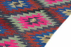 A vintage handmade Turkish kilim rug featuring a geometric pattern in vibrant neon and earth tones.