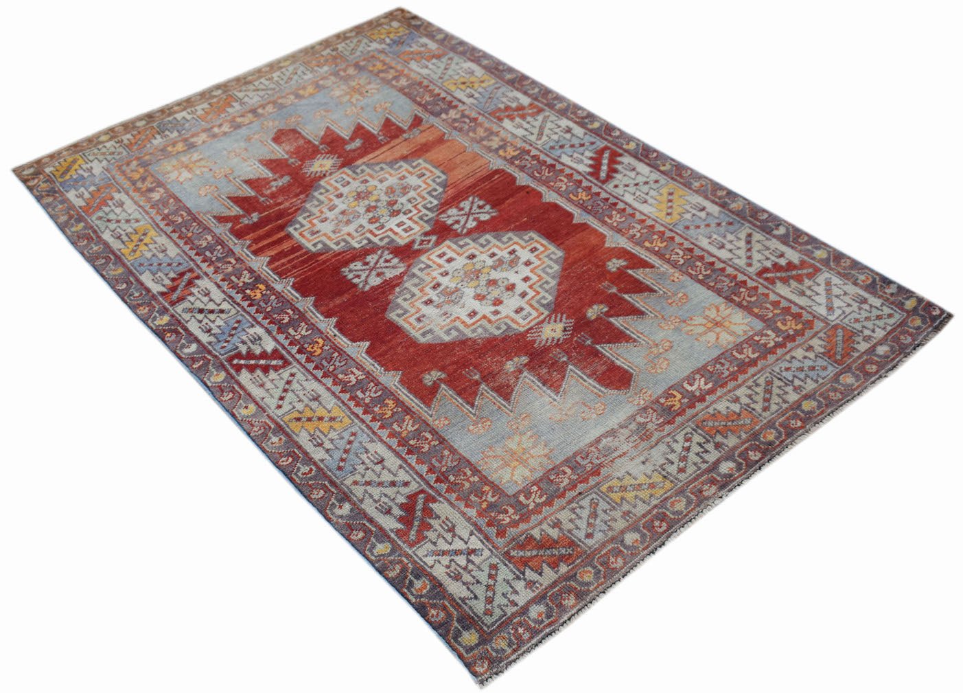 A vintage handmade Turkish Kula rug featuring geometric patterns in red, blue, and yellow tones.