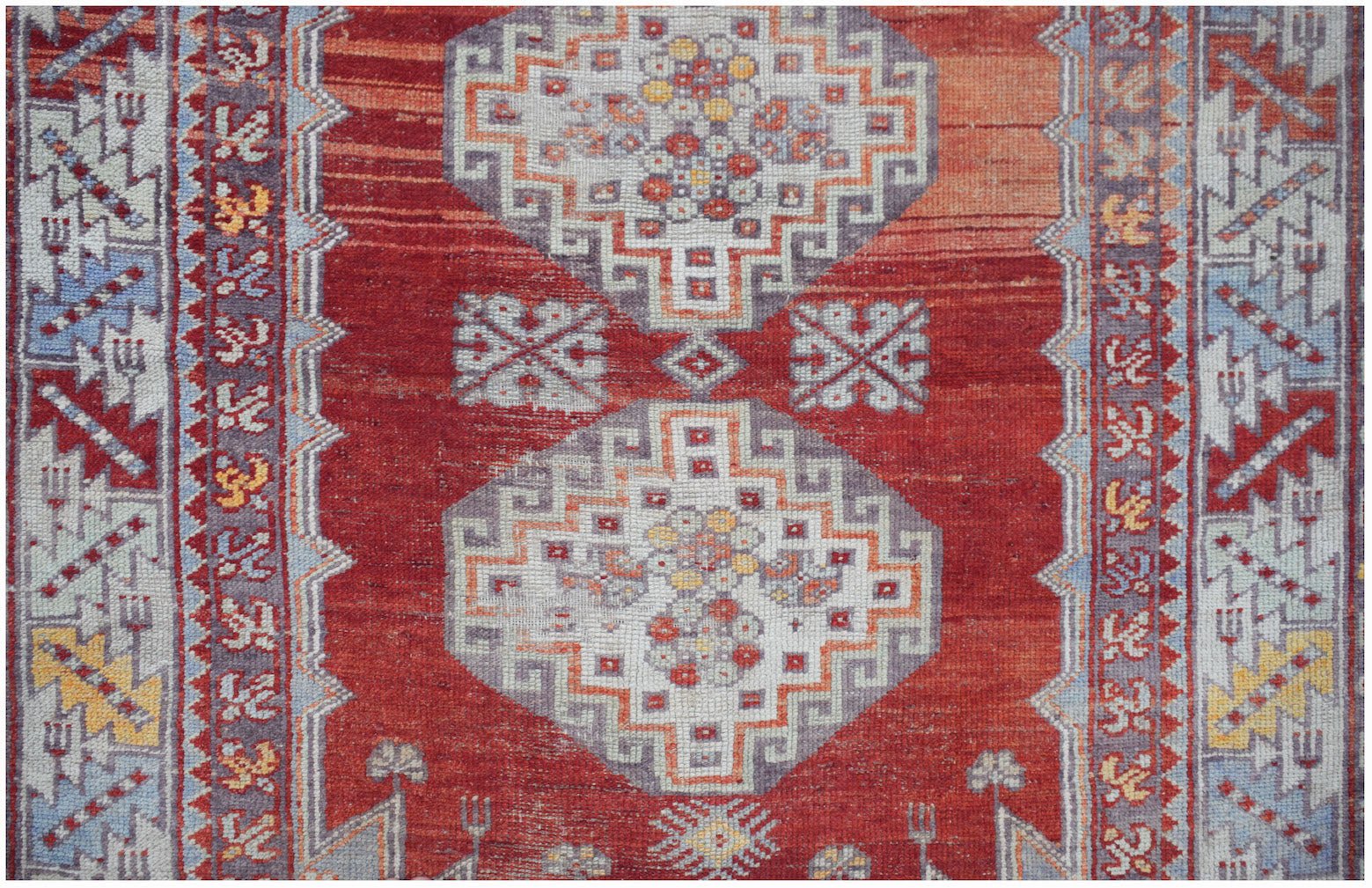 A vintage Turkish Kula rug featuring geometric patterns in red, orange, and blue tones.