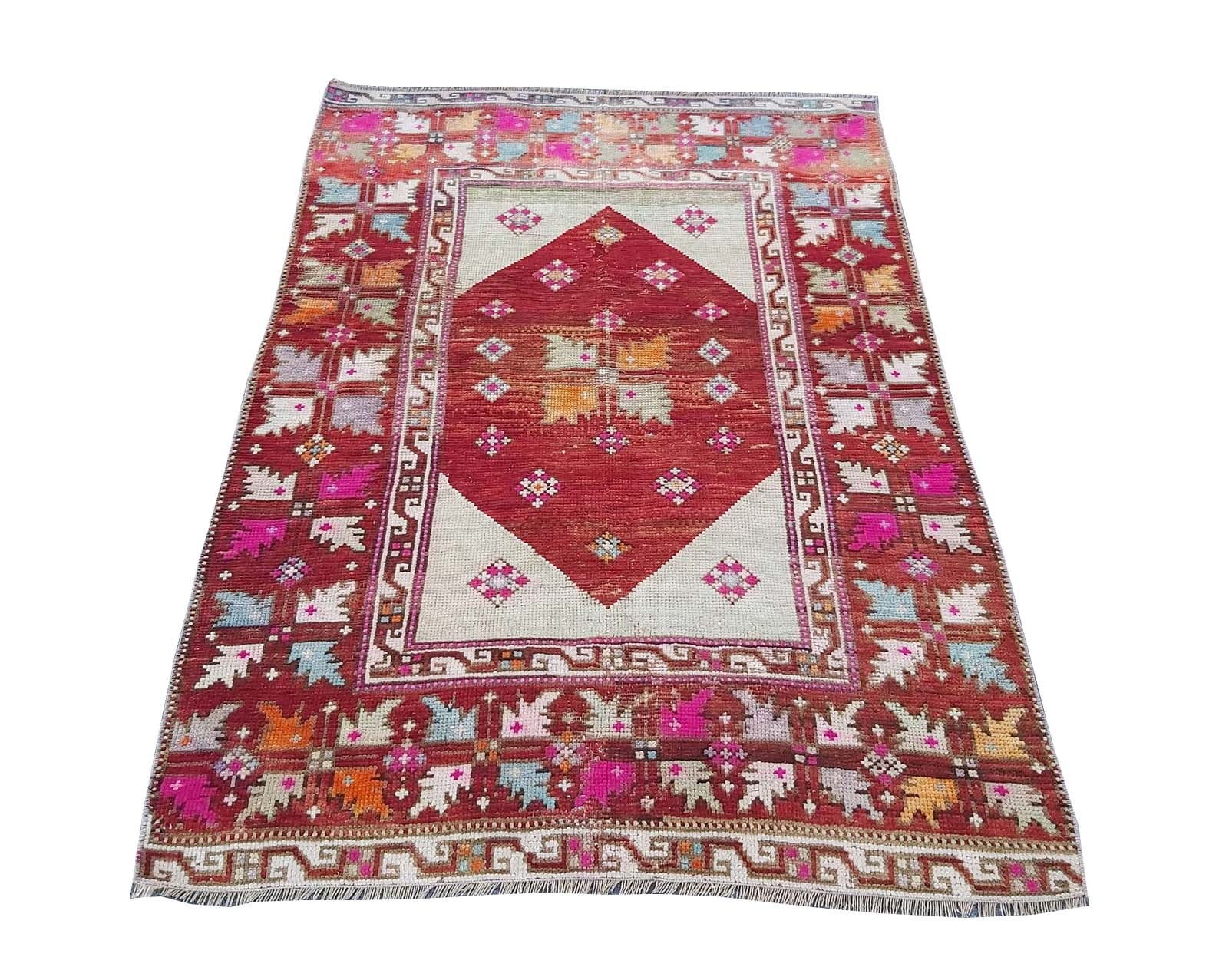 A vintage Turkish Kula rug featuring a red diamond medallion on a cream field with geometric motifs.
