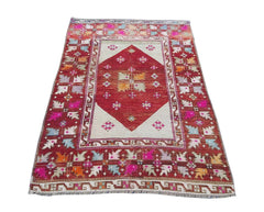 A vintage Turkish Kula rug featuring a red diamond medallion on a cream field with geometric motifs.