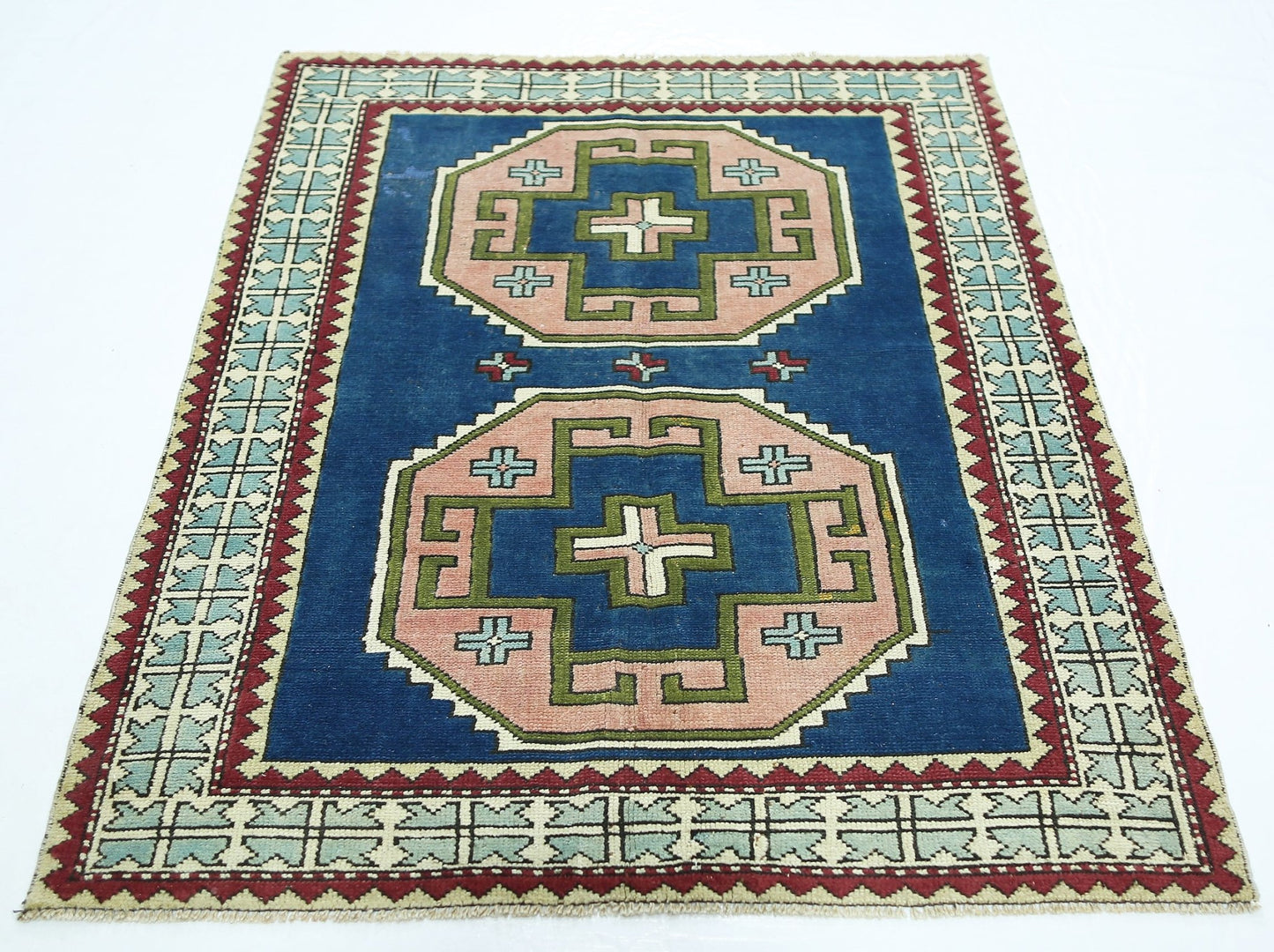 A vintage handmade Turkish rug featuring two large geometric medallions on a deep blue background.