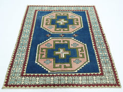 A vintage handmade Turkish rug featuring two large geometric medallions on a deep blue background.