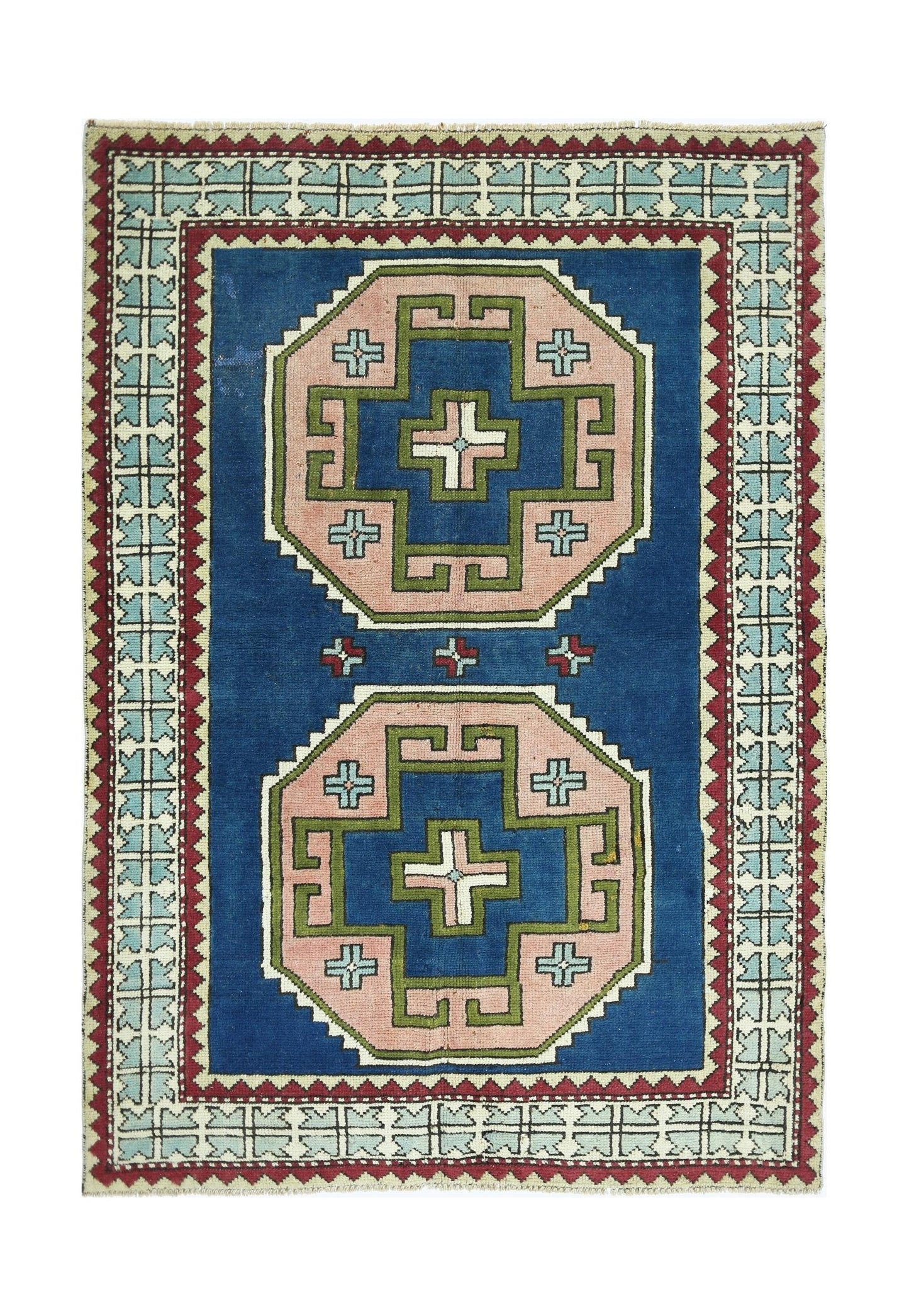 A vintage handmade Turkish rug featuring two pink and green geometric medallions on a blue field.