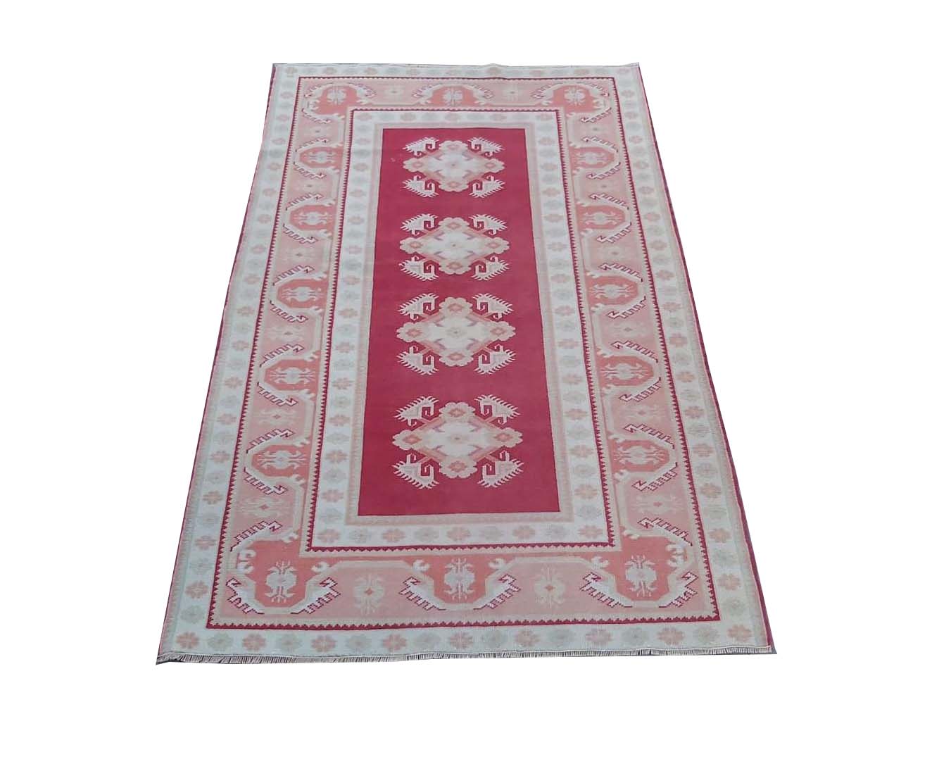 A vintage Turkish Milas rug featuring a red center with geometric patterns and a light border.