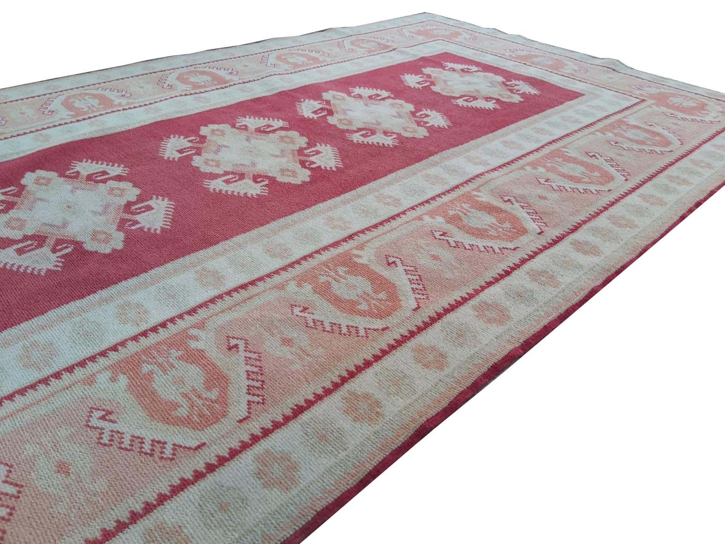 A vintage Turkish Milas rug featuring geometric patterns in shades of red, cream, and grey.