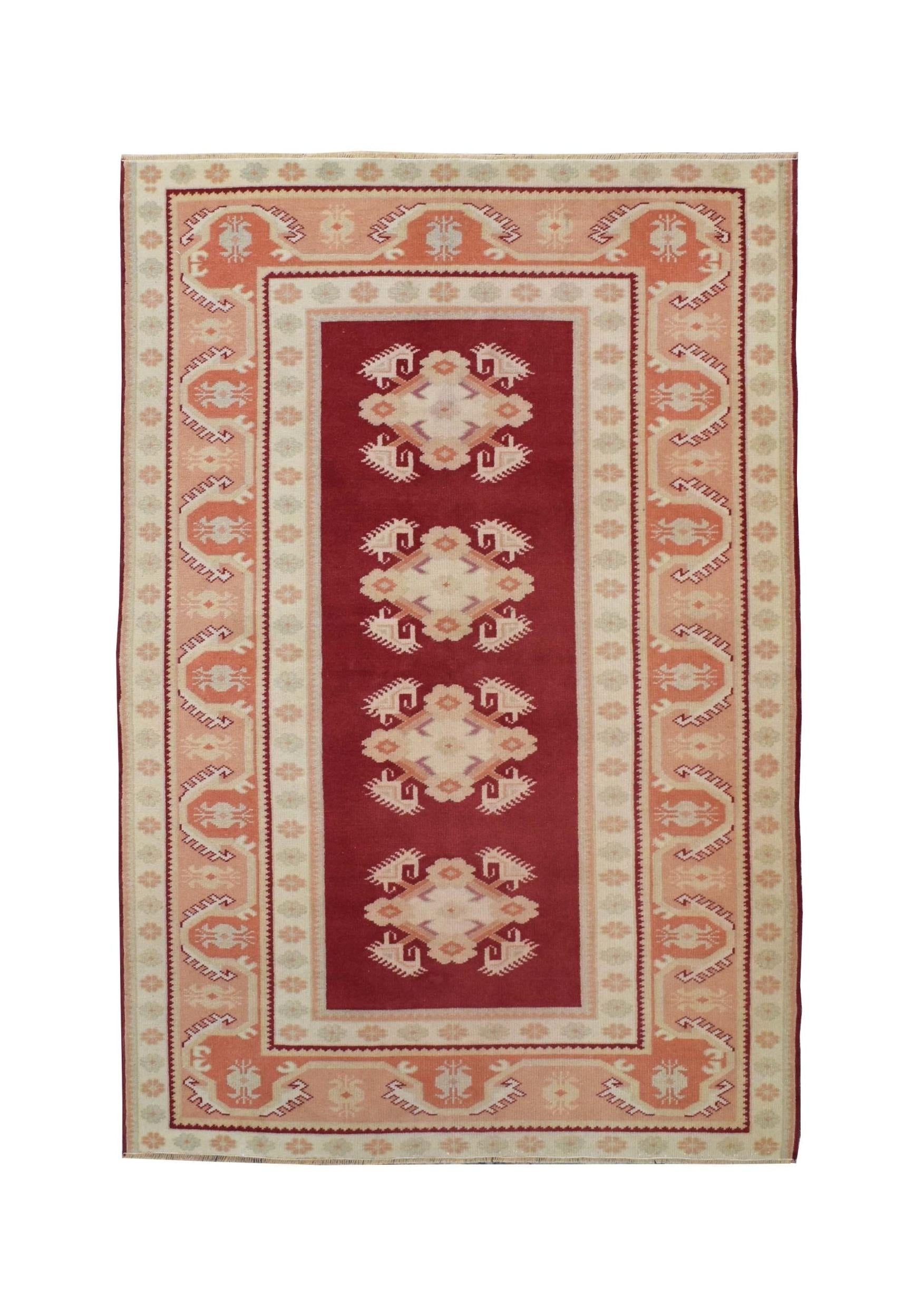 A vintage Turkish Milas rug featuring a deep red field with four geometric medallions.