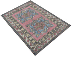 A vintage handwoven Turkish Milas rug featuring geometric medallions in pink and blue tones.