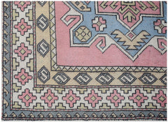 A vintage handwoven Turkish Milas rug featuring a geometric pattern in pink, blue, and cream.