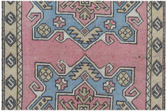 A vintage handwoven Turkish Milas rug featuring geometric patterns in pink, blue, and beige.
