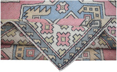 A vintage handwoven Turkish Milas rug featuring geometric patterns in pink, blue, and cream.