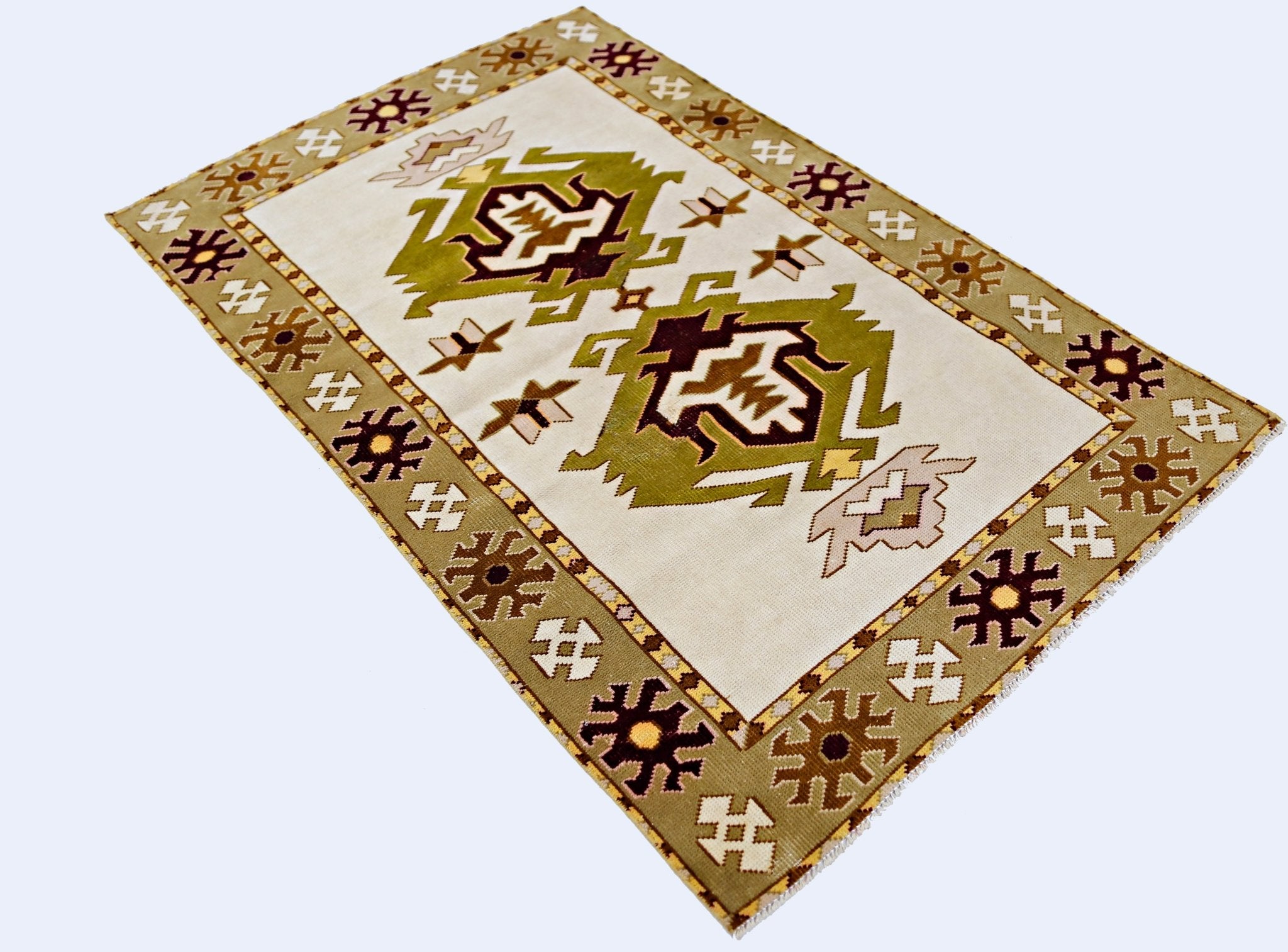A vintage handmade Turkish Milas rug featuring geometric olive green and brown motifs on a cream base.