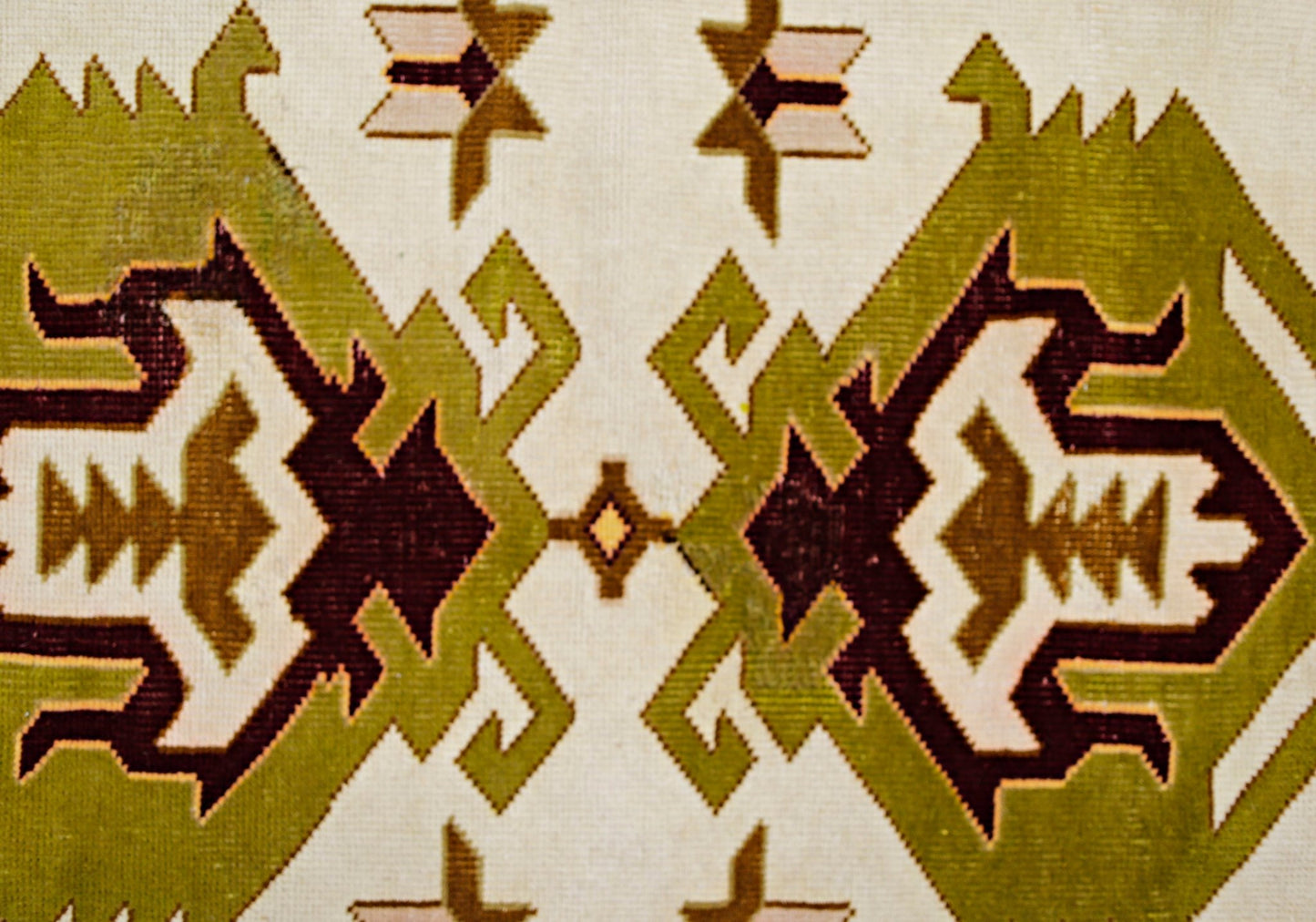 A vintage Turkish Milas rug featuring a geometric pattern in olive green, brown, and cream.
