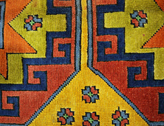 A close-up of a vintage Turkish rug featuring geometric patterns in vibrant yellow, red, and blue.