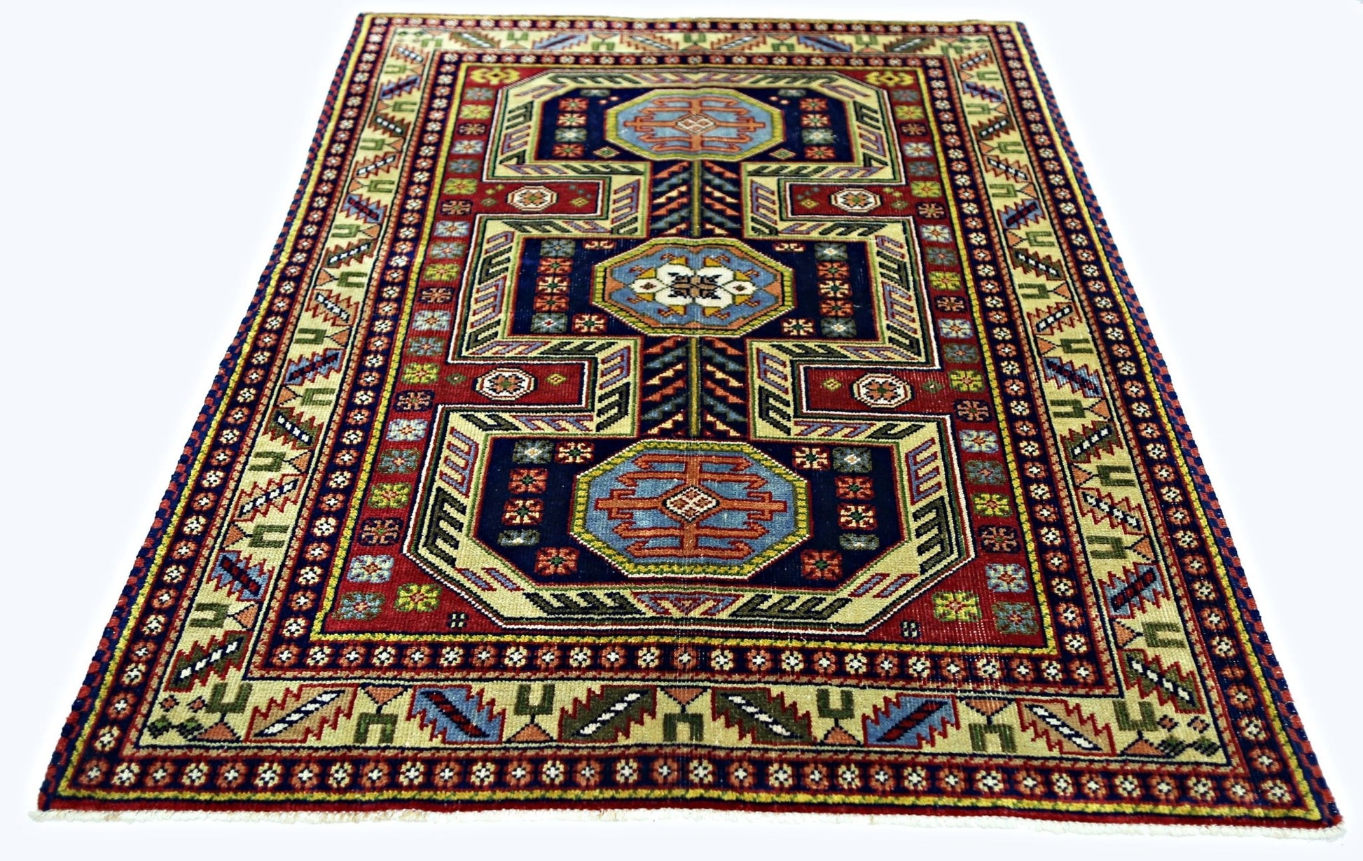 A handmade vintage Turkish wool rug featuring a geometric pattern in blue, red, and cream tones.