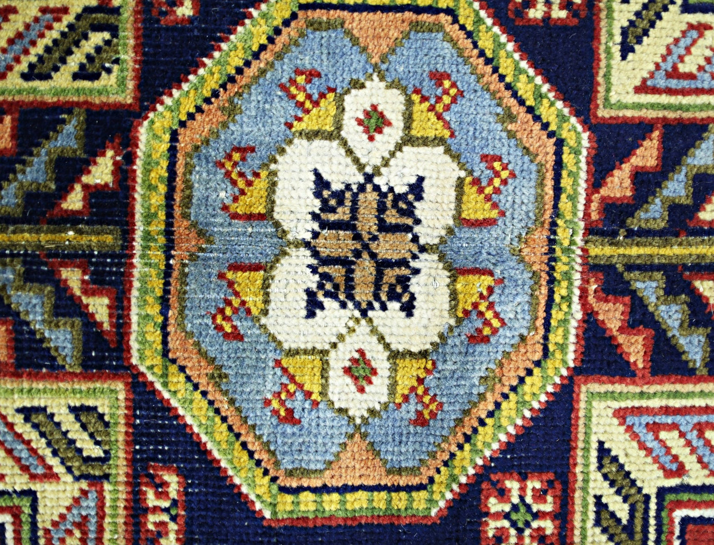 A close-up of a vintage handmade Turkish rug featuring a central geometric medallion in blue.