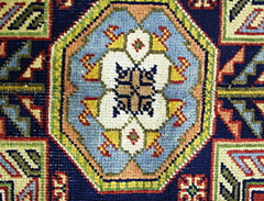 A close-up of a vintage handmade Turkish rug featuring a central geometric medallion in blue.