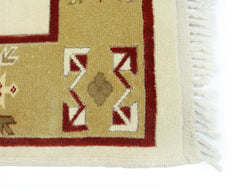 A corner detail of a vintage Turkish Milas rug featuring geometric patterns in red and tan wool.