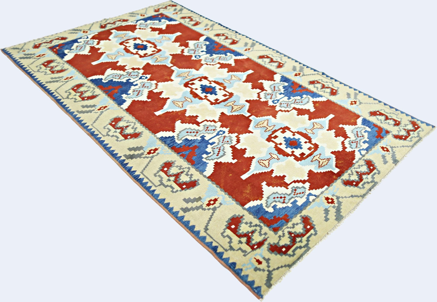 A rectangular vintage Turkish rug featuring a geometric pattern in red, blue, and cream tones.