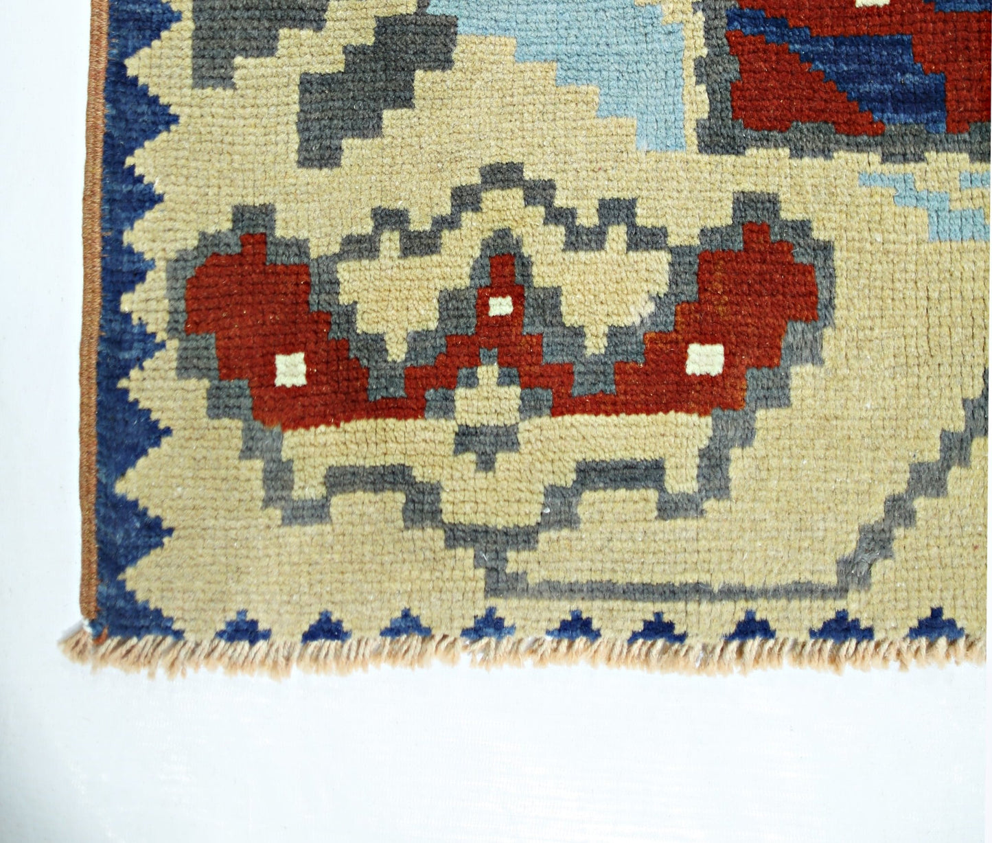 A close-up of a vintage handmade Turkish wool rug featuring geometric patterns in red and blue.