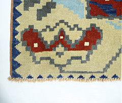 A close-up of a vintage handmade Turkish wool rug featuring geometric patterns in red and blue.