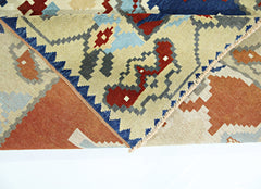 A folded vintage Turkish rug featuring a geometric pattern in shades of red, blue, and beige.