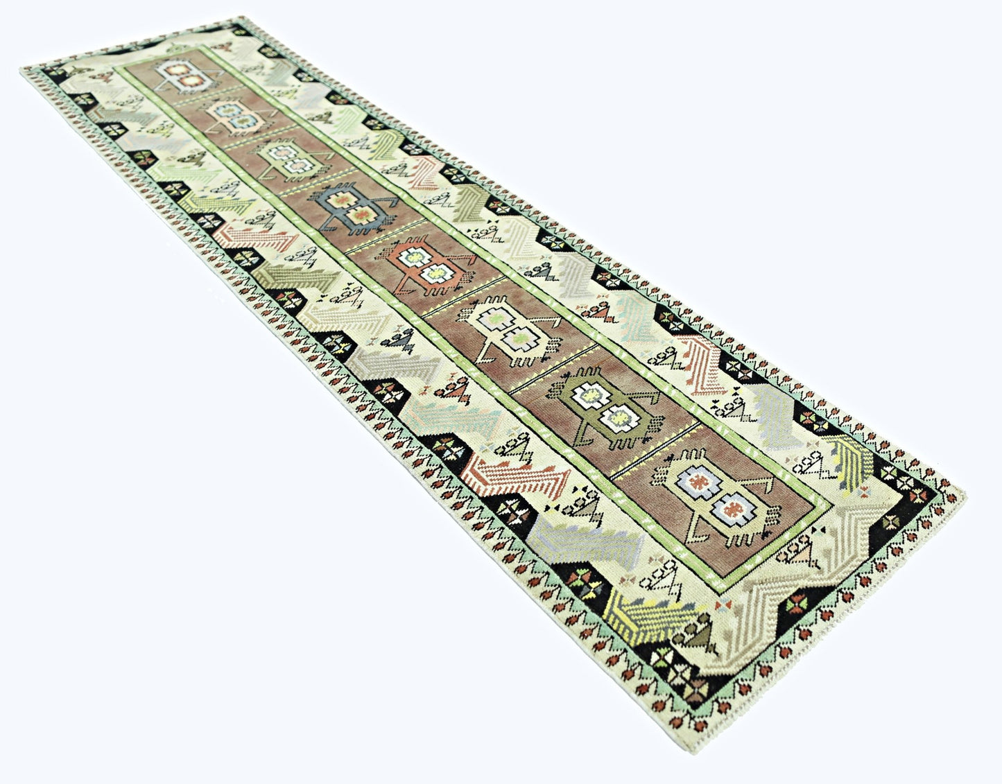 A vintage handmade Turkish runner rug featuring geometric motifs in earthy tones on a light field.