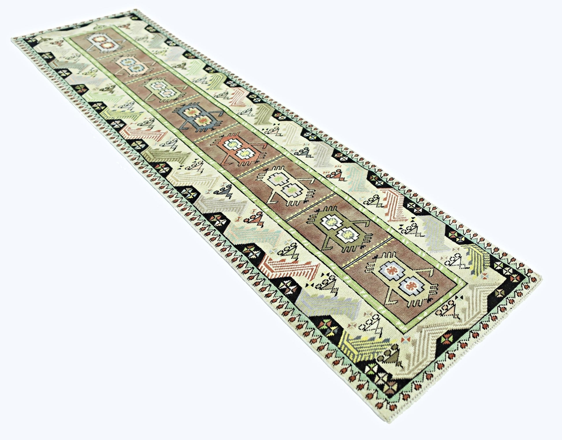 A vintage handmade Turkish runner rug featuring geometric motifs in earthy tones on a light field.