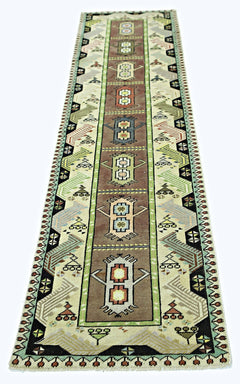 A vintage handmade Turkish runner rug featuring geometric motifs in brown, green, and cream tones.