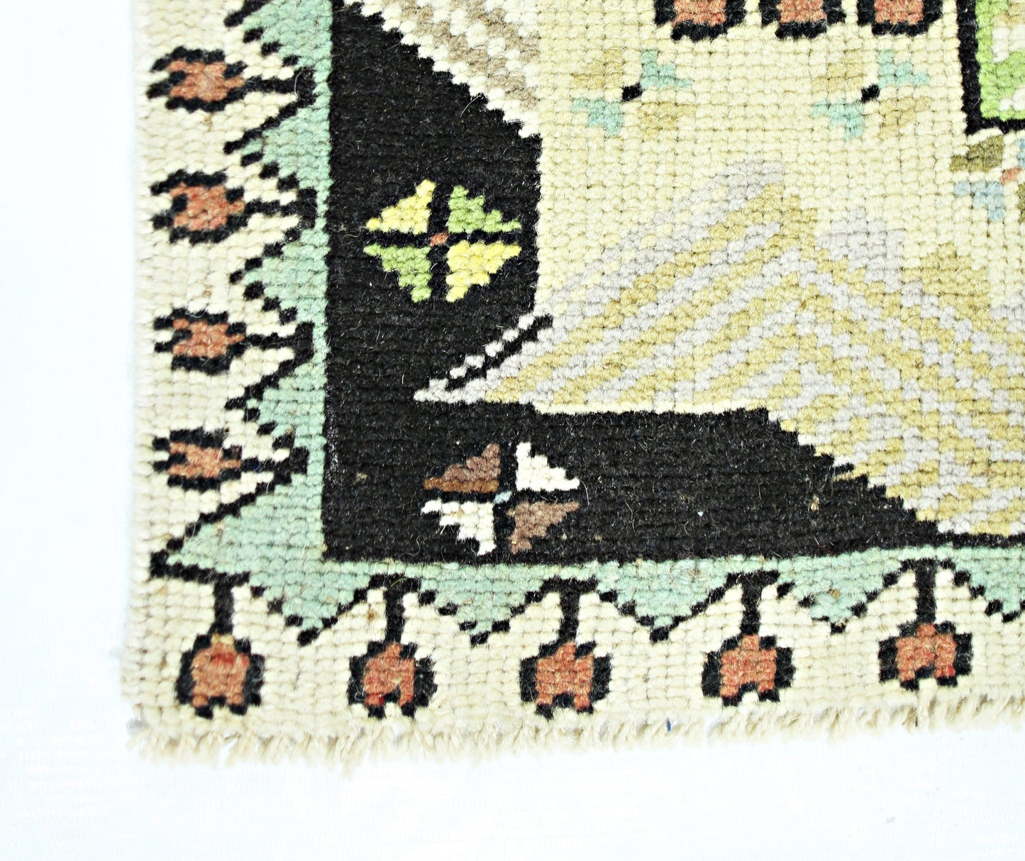 A corner detail of a vintage handmade Turkish runner featuring geometric patterns in wool.