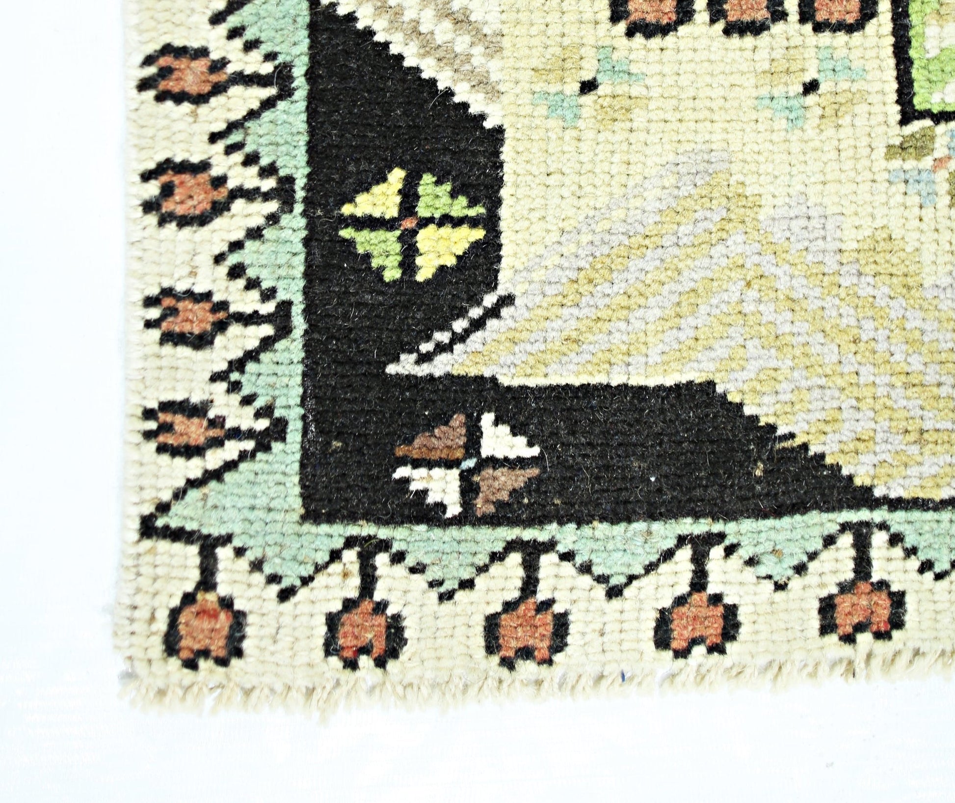 A corner detail of a vintage handmade Turkish runner featuring geometric patterns in wool.