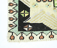 A corner detail of a vintage handmade Turkish runner featuring geometric patterns in wool.
