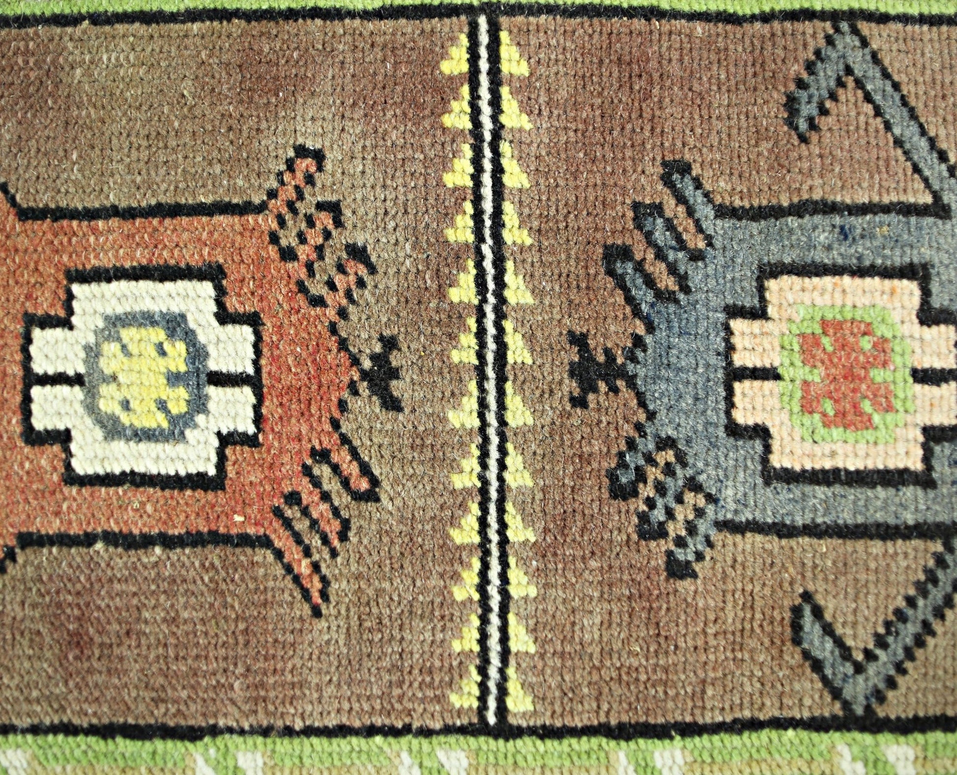 A close-up of a vintage Turkish runner featuring geometric motifs in brown, orange, and blue wool.