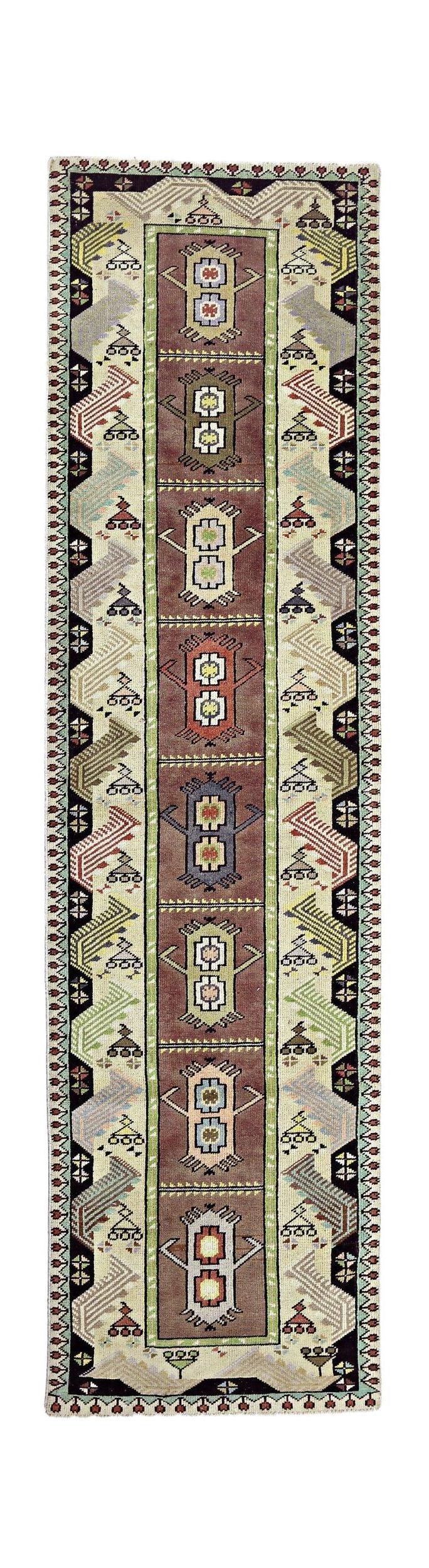 A vintage Turkish runner rug featuring a central row of geometric motifs on a brown field.