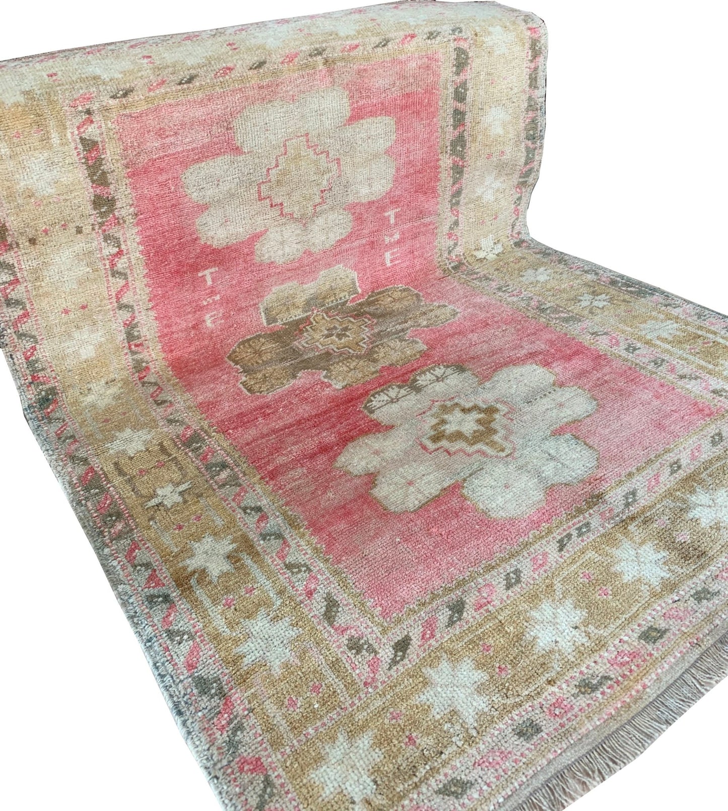 A vintage handmade Turkish Oushak rug featuring a pink field with tribal floral motifs.