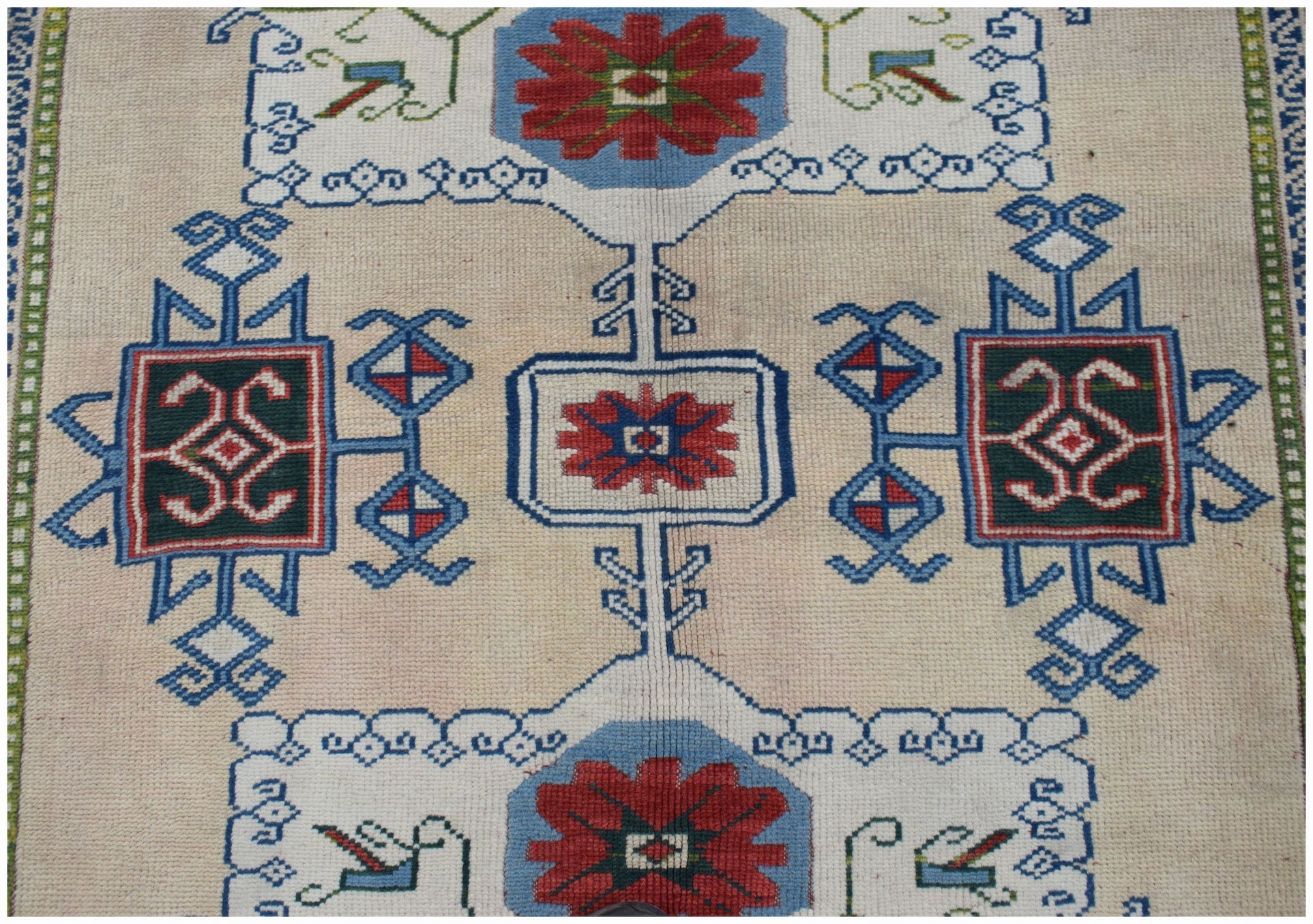 A vintage Turkish Oushak rug featuring a traditional geometric pattern in red, blue, and green.