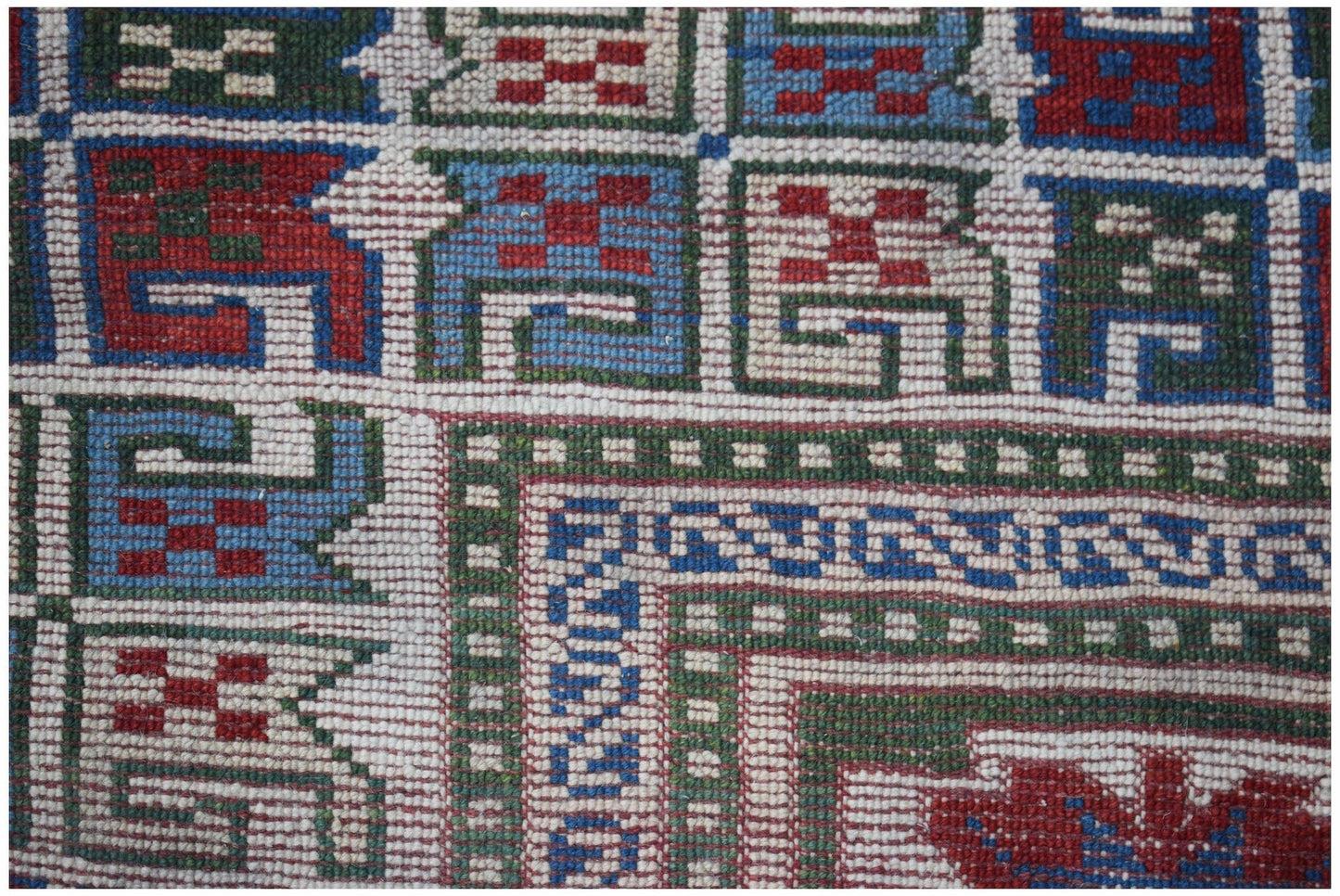 A close-up of a vintage Turkish Oushak rug featuring a geometric pattern in red, blue, and green.