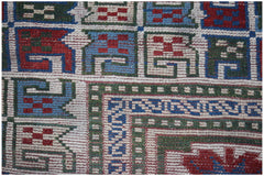 A close-up of a vintage Turkish Oushak rug featuring a geometric pattern in red, blue, and green.