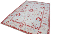 A vintage Turkish Oushak rug featuring a traditional red and light blue pattern on a cream field.