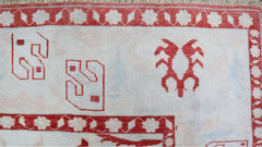 A vintage Turkish Oushak rug featuring red geometric motifs on a light cream wool background.