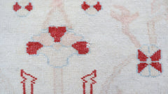 A close-up of a vintage Turkish Oushak rug featuring a traditional red floral pattern on cream.