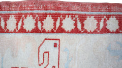 A close-up of a vintage Turkish Oushak rug featuring a red border with circular motifs.