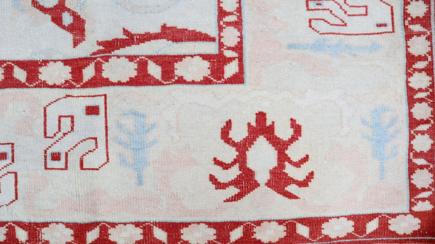 A vintage Turkish Oushak rug featuring a cream field with red geometric motifs and blue accents.